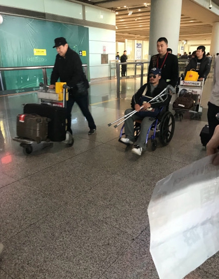 吴京手拿拐杖坐轮椅现身机场 表情严肃疑似腿受伤