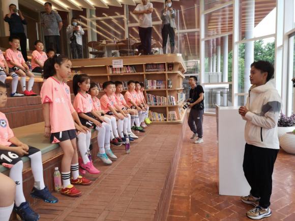 在“红房子”与小学生赛足球，王霜推介“咸伙计”为家乡代言