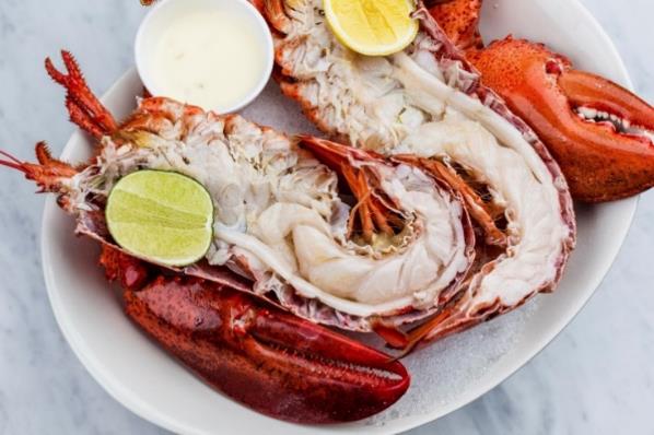 A plate of lobster with lemons and saucesDescription automatically generated